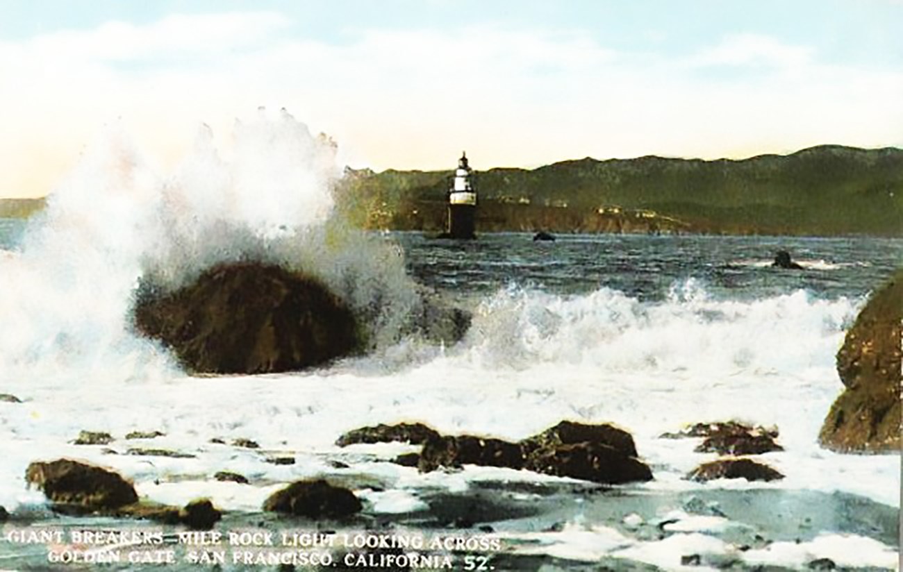 Historic colored postcard of waves crashing over rocks with Lands End shore in background.