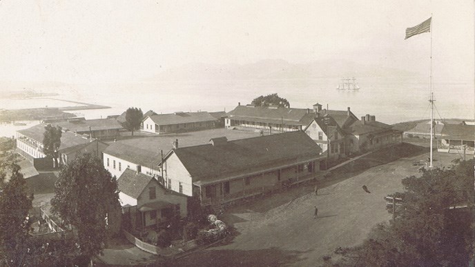 historic photo of military post with one-story wood-frame buildings centered around an open space