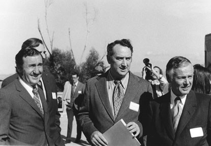 group of men in suits posing for outdoor photo