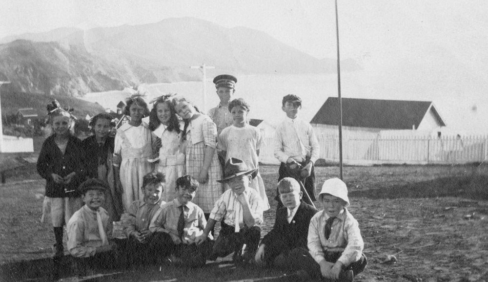 a group  of smiling boys and girls near ocean and cliffs