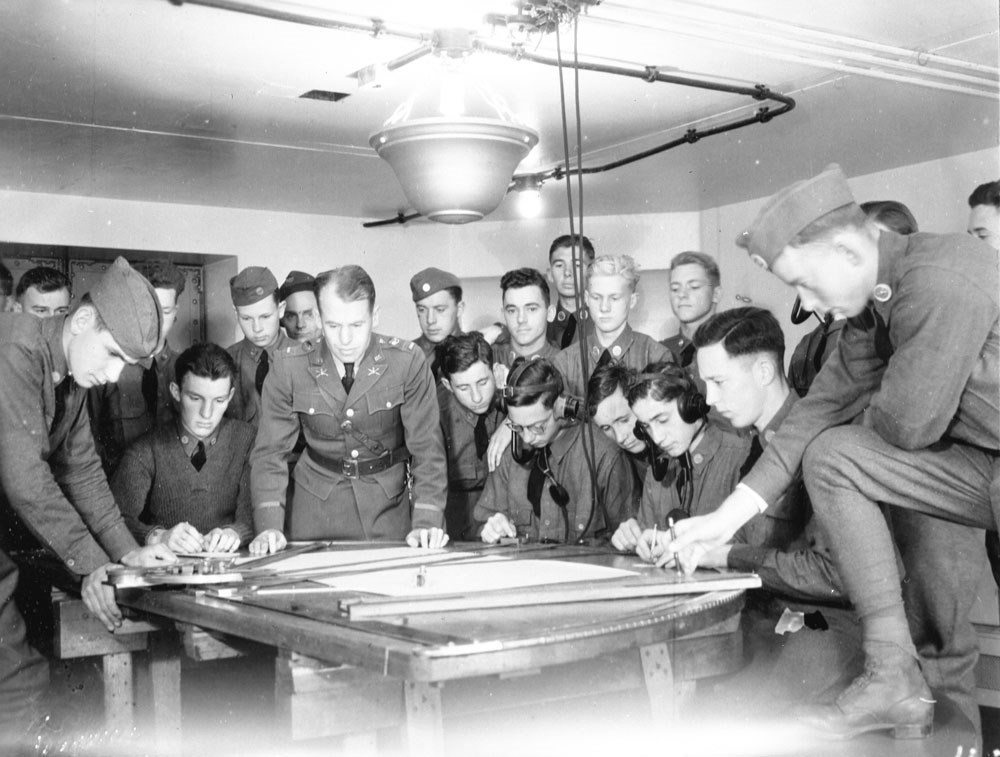 a crowded room of soldiers reviewing a table