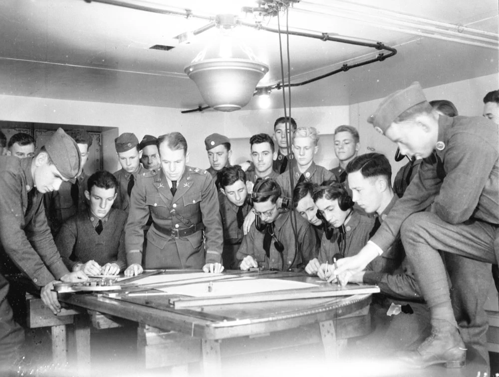 Fort-Barry-men-around-firing-coordinates_2019 a crowded room of soldiers reviewing a table