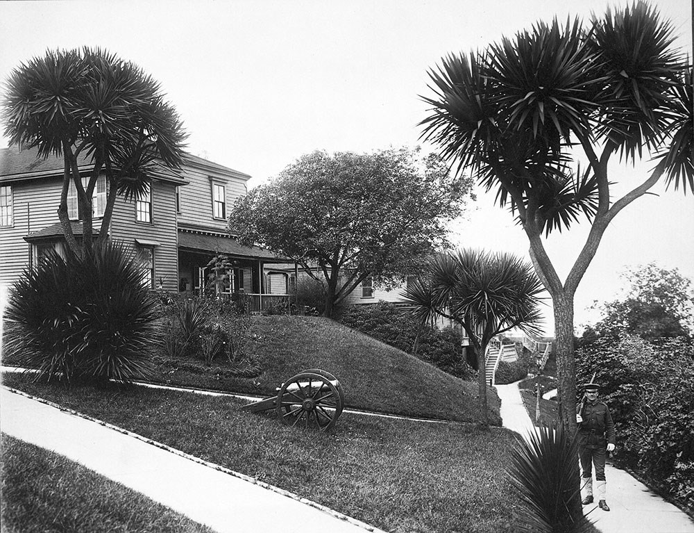 soldier on patrol in a garden with house in the background