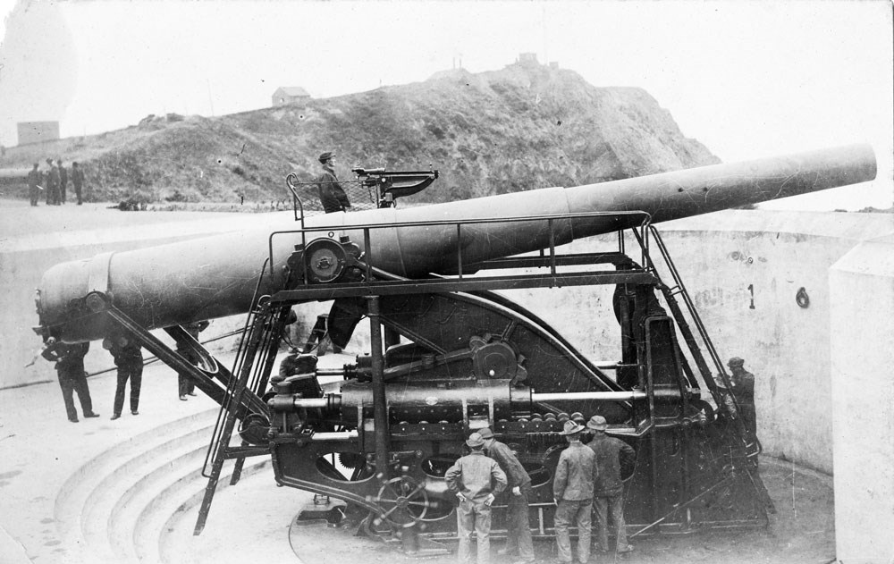 soldiers manning a large metal gun that is perched on a concrete wall