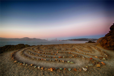 Colored photo of rocks aligned in circular fashion on beach.