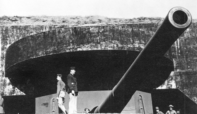soldiers standing in front of large gun