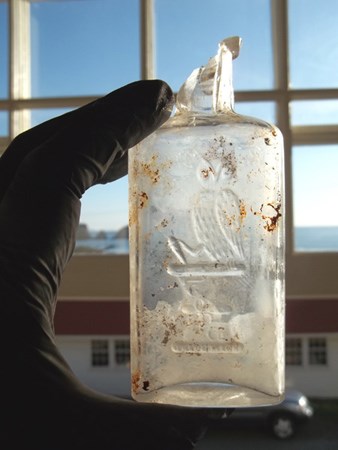 image of a historic small glass bottle with an owl etched on the front