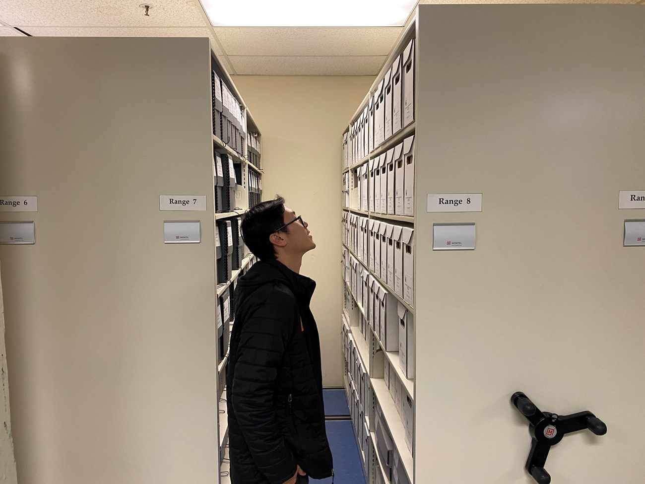 a person looks at objects inside of the archives compact shelving