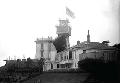 Ornate wooden house with water tower perched at cliff's edge.