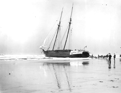 Wooden ship with masts listing to one side, stuck on a beach. Wooden ship with masts listing to one side, stuck on a beach.