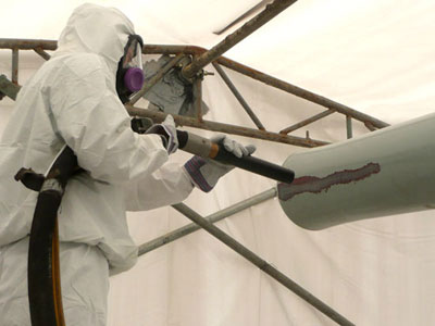man blasting paint off of historic cannon