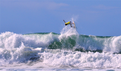 Surfer leaping into the air on a surfboard above the water.