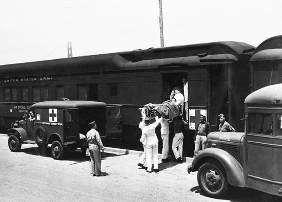 Medics during World War II transporting a wounded soldier from the U.S. Army hospital train that ran along Crissy Field. Notice the tip of the Golden Gate Bridge in the background. (photo circa 1944)