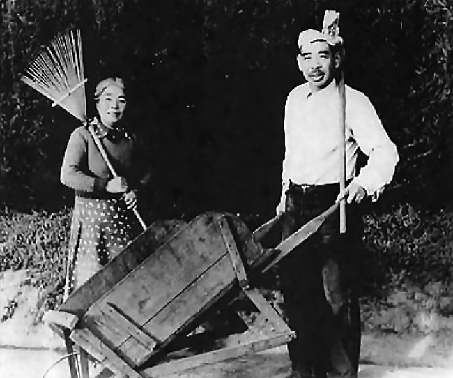 man holds barrel and woman holds rack in front of bush