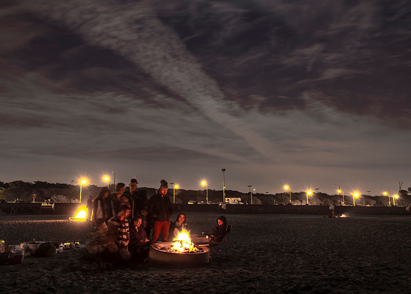 People at dusk with a fire in a fire pit