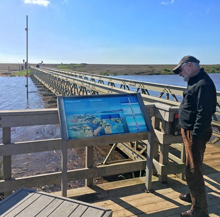 Visitor viewing sea level rise exhibit at bridge to Rodeo Beach