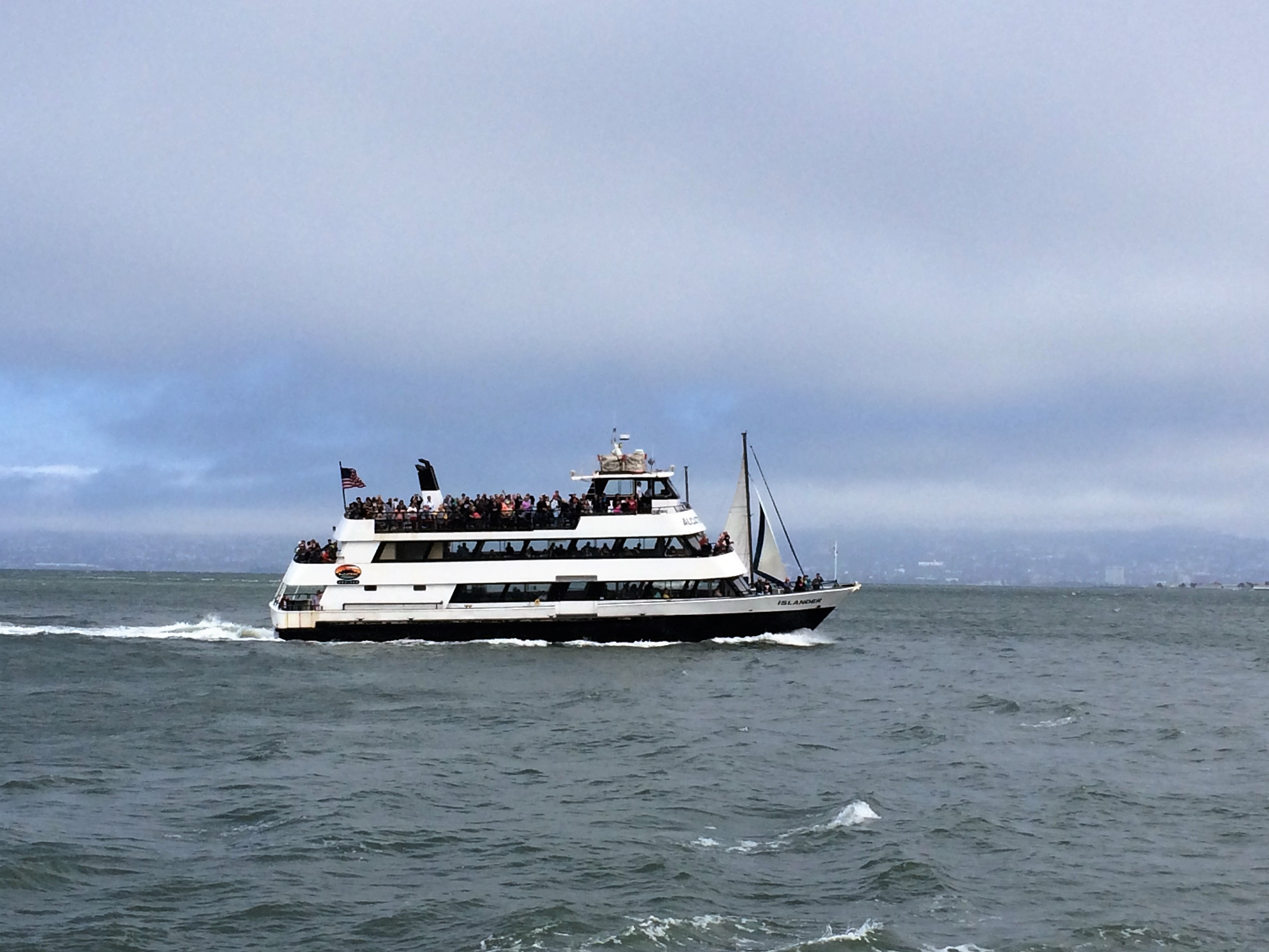 Passenger ferry moving in water with a grey sky in the background.