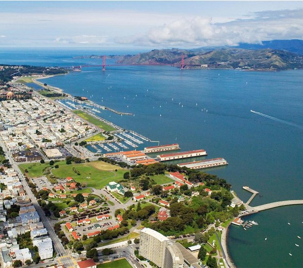Fort Mason Aerial Aerial view of Fort Mason. Foreground shows historic tan buildings and piers with blue water of San Francisco Bay and international red Golden Gate Bridge in the distance.