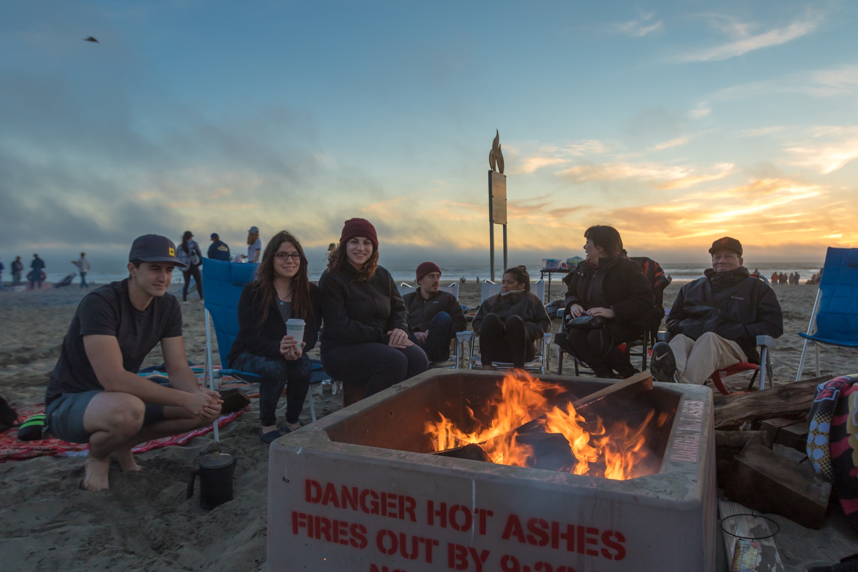 Small group sits around beach fire at dusk. Small group sits around beach fire at dusk.