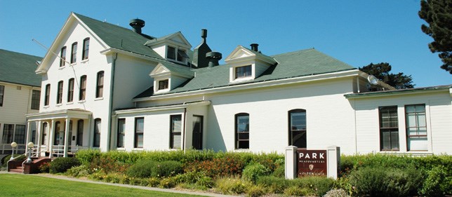 white building with green lawn and brown sign white building with green lawn and brown sign