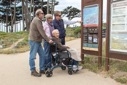 A man in a wheelchair along side his family looks at an information panel.