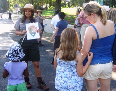 A park ranger explains the symbolism of the National Park Service Arrowhead to young visitors.