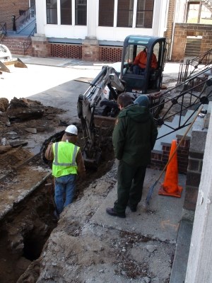 Park rangers supervise resource-sensitive construction work at Fort Jay.  Revealed within the trench is a circular brick air shaft into one of the subterranean chambers.