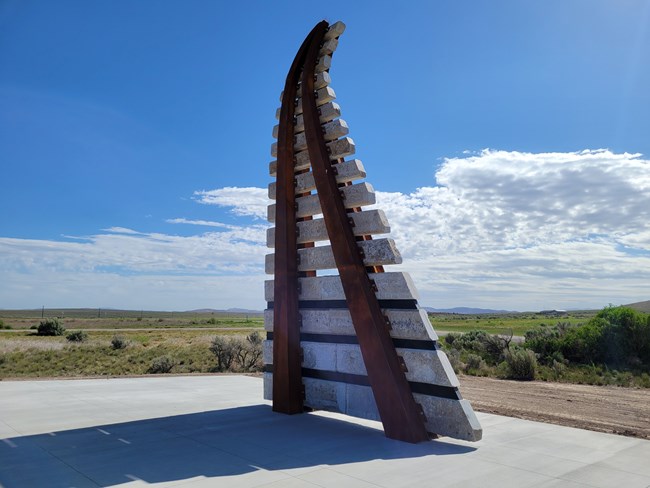 Railroad track sculpture curving up into the sky.