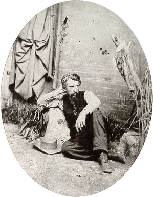 Photographer A. J. Russell sits next to a rock.