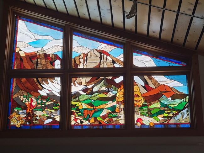 A colorful stained glass representation of park icons like bristlecone pines and wheeler peak