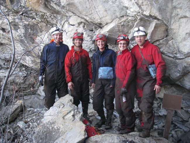 five people standing in muddy clothes