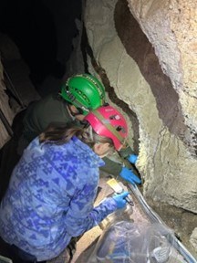 two people crouched along cave wall