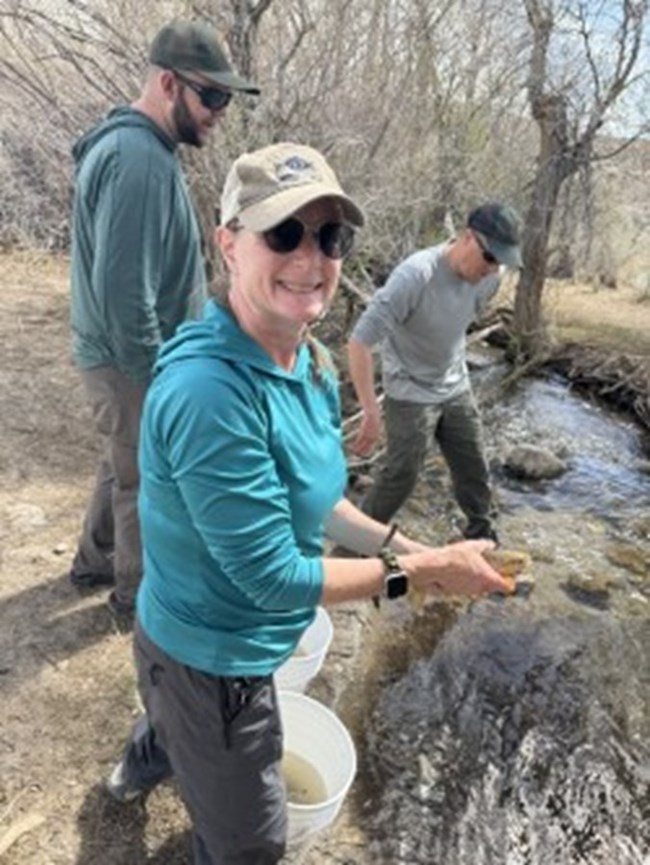 person holding fish next to creek