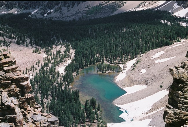 An emerald-colored lake sits below the ridgeline of Baker Peak.