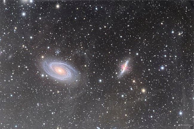 A field of stars surrounds two different galaxies in the night sky