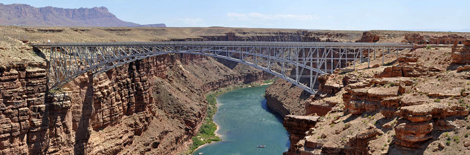 View looking downriver at Navajo Bridge spanning a green Colorado River 466 feet below.