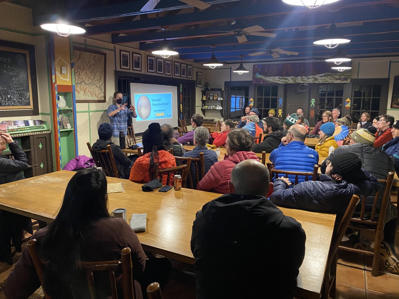 A room full of people listen to a presentation in an historic cantina.