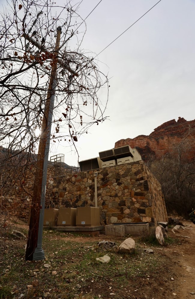 Electrical lines by a stone building.