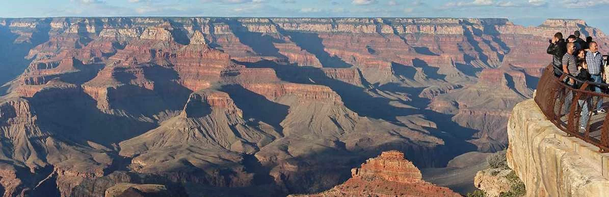 Mather Point 17 a group of sightseers behind a guardrail at a scenic overlook are viewing the vast and colorful Grand Canyon landscape.