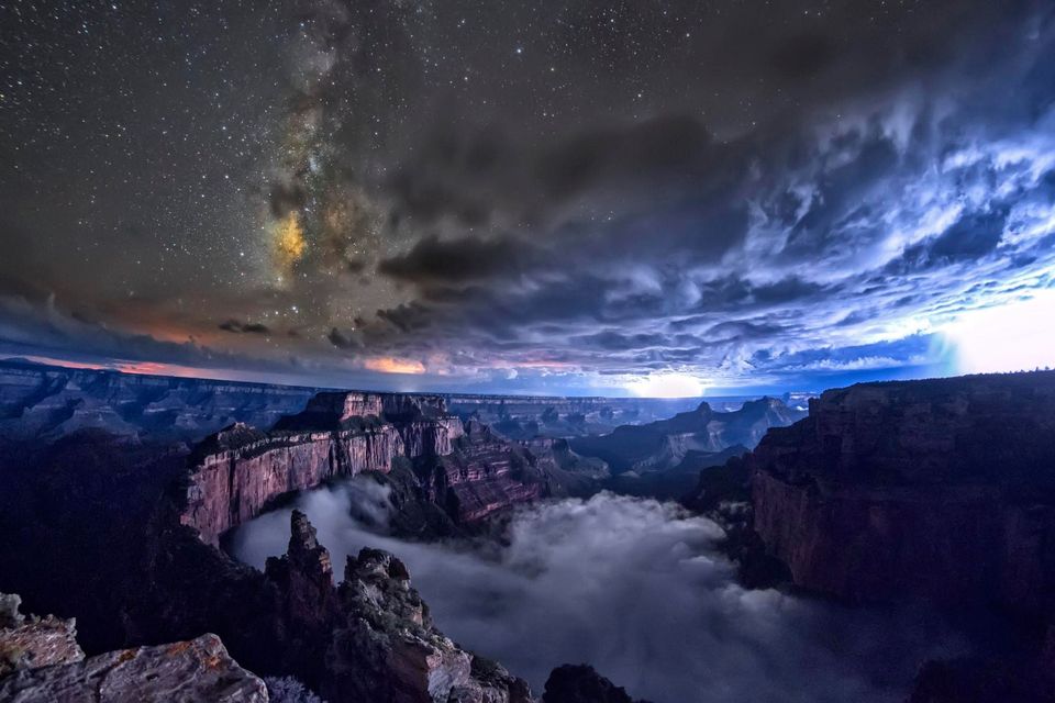 Wotan's Throne in the foreground. The Milky Way peaks out through a thunderstorm. Lightning strikes nearby.