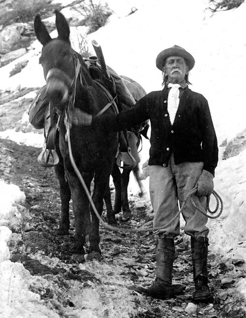 John Hance A black and white photograph of a man standing next to a mule.