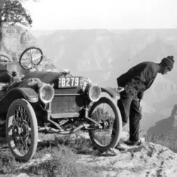 Old car on edge of canyon, man peering over edge