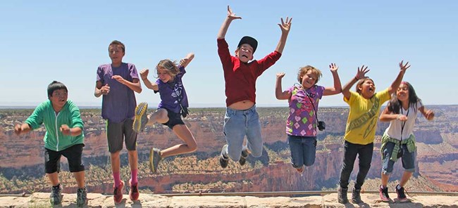 Seven youth jumping up in the air with Grand Canyon as a background behind them Seven youth jumping up in the air with Grand Canyon as a background behind them