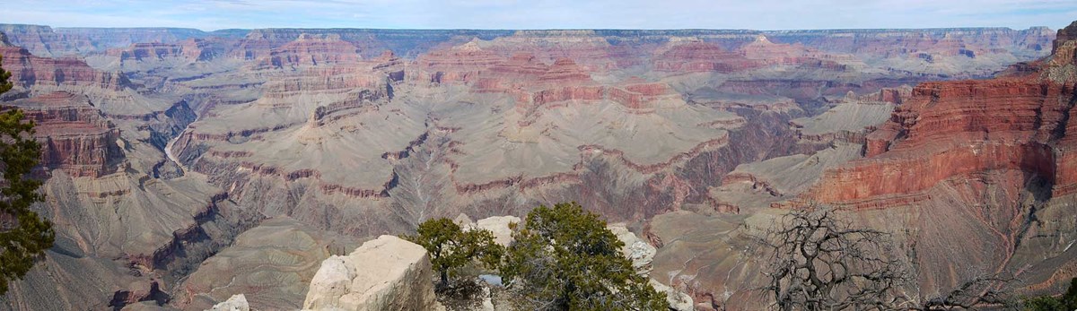 Grand Canyon from Pima Point includes steep cliffs on both left and right sides of the view a limestone pillar in the foreground and colorful peaks in the distance