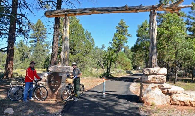 A park ranger and another participant pose for a photo at the Grand Canyon National Park Entrance Arch on a recently completed Tusayan to Grand Canyon National Park Visitor Center Greenway during Bike Your Park Day on Sept. 24, 2016.