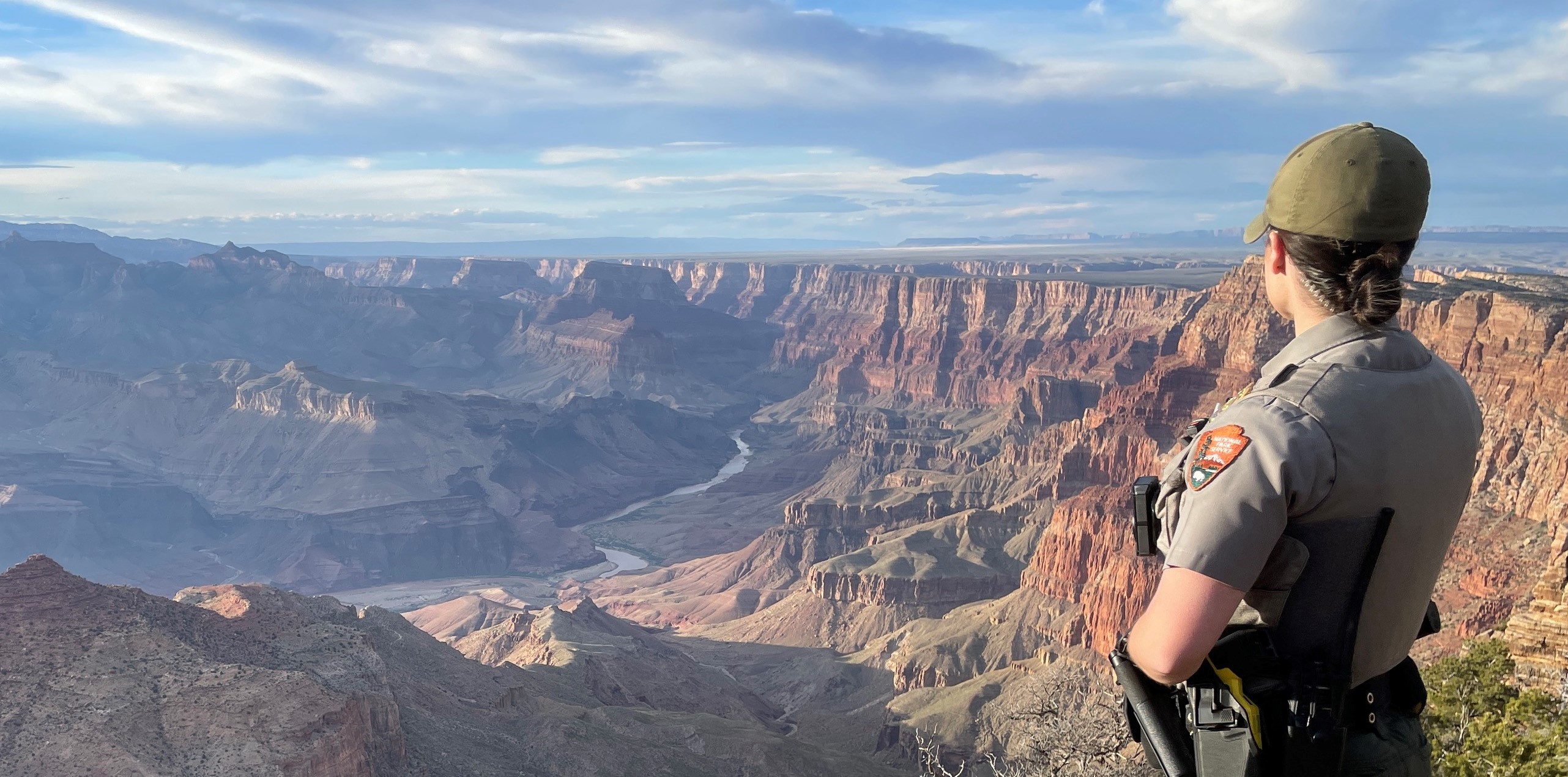 A ranger stands at the rim of the canyon looking into the canyon vista