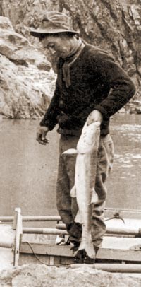 17152 EMERY KOLB HOLDING 25 LB. COLORADO RIVER SALMON (COLORADO SQUAWFISH) BOAT BEHIND. SEPT 1911 KOLB BROS PHOTO