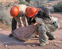CREC crew of three moving a large slab of rock.