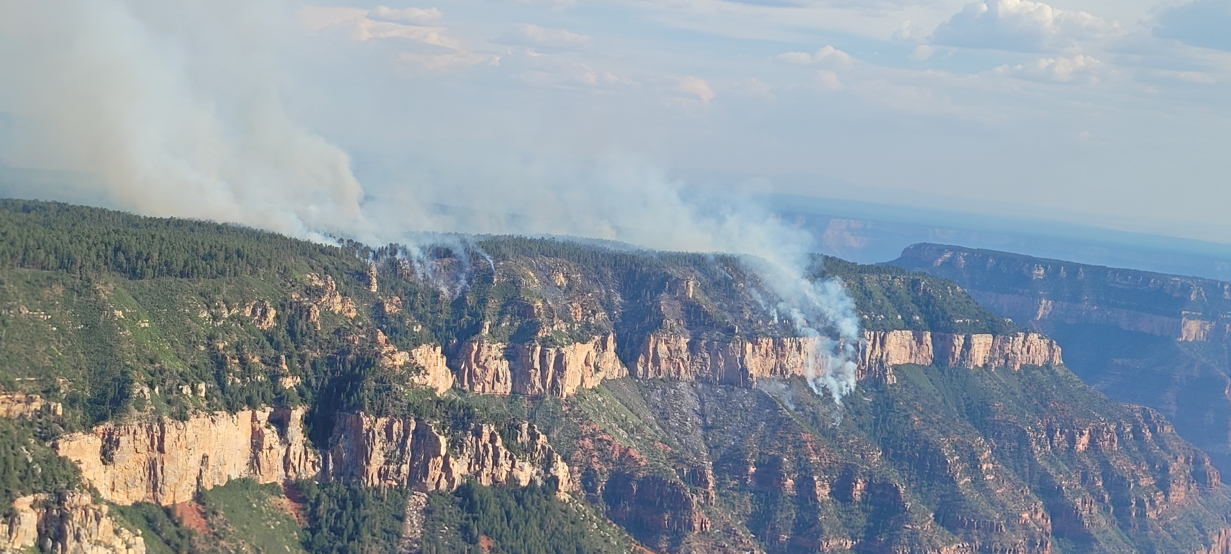 The Dragon Fire is seen below the rim of the canyon with smoke billowing
