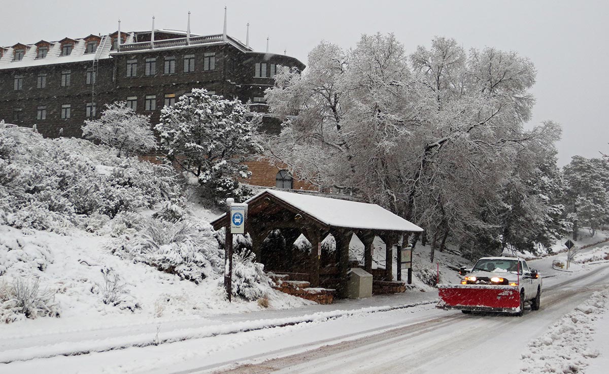 Snow-packed and icy road with snowplow by Train Depot Shuttle Bus stop